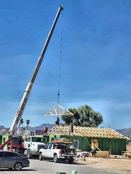Crane lifting roof trusses onto a residential build