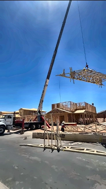 Crane lifting a roof truss during a construction project